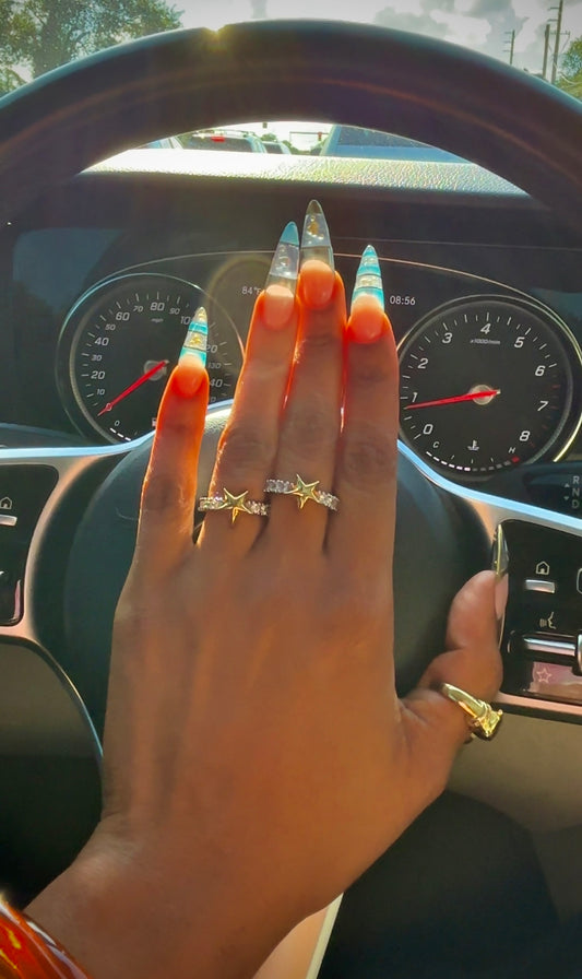 Hand with decorated nails and rings on a car dashboard